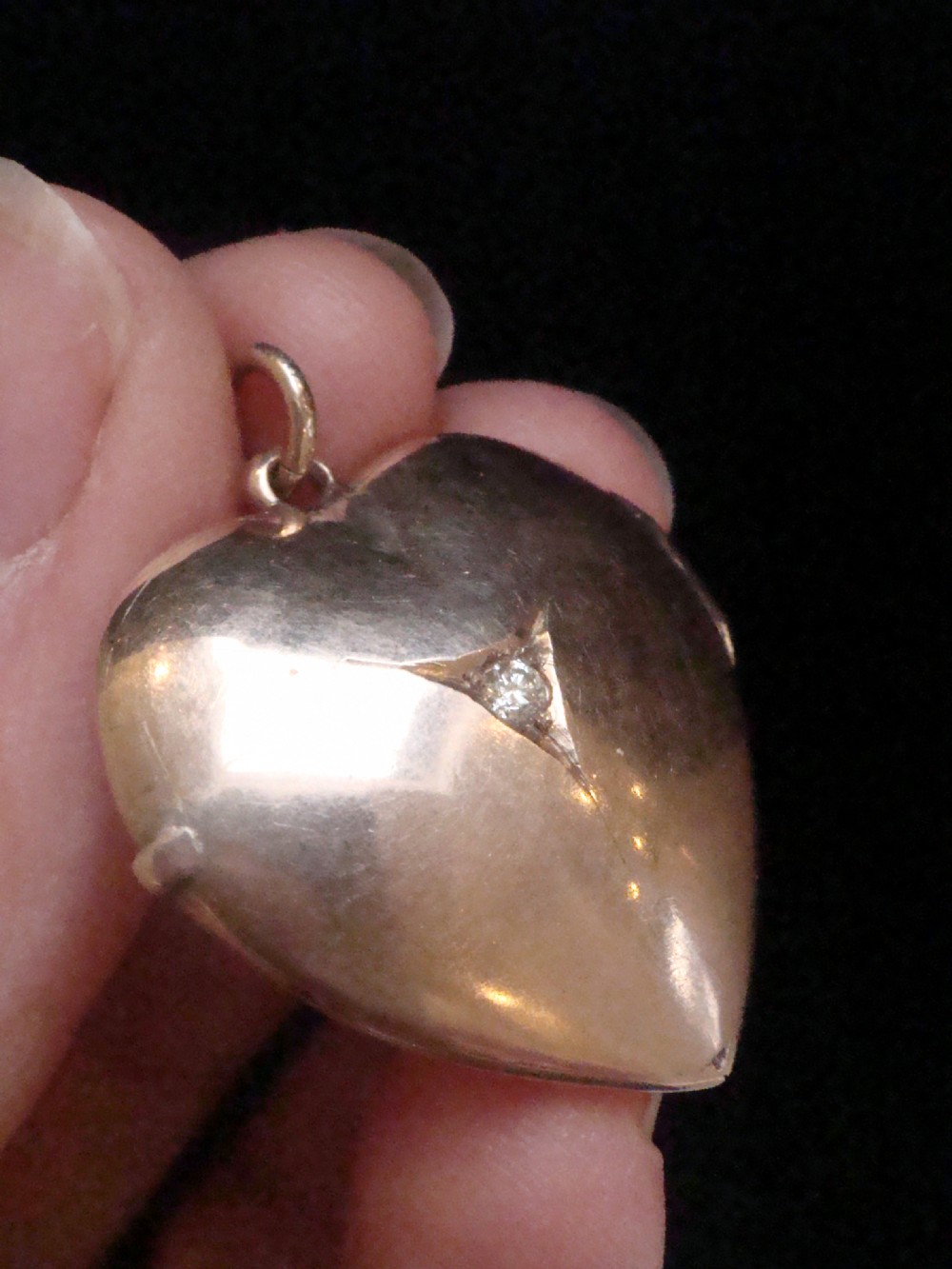 An Edwardian 9ct gold puffed heart locket featuring a centrally inset old cut diamond within a starburst setting. View II