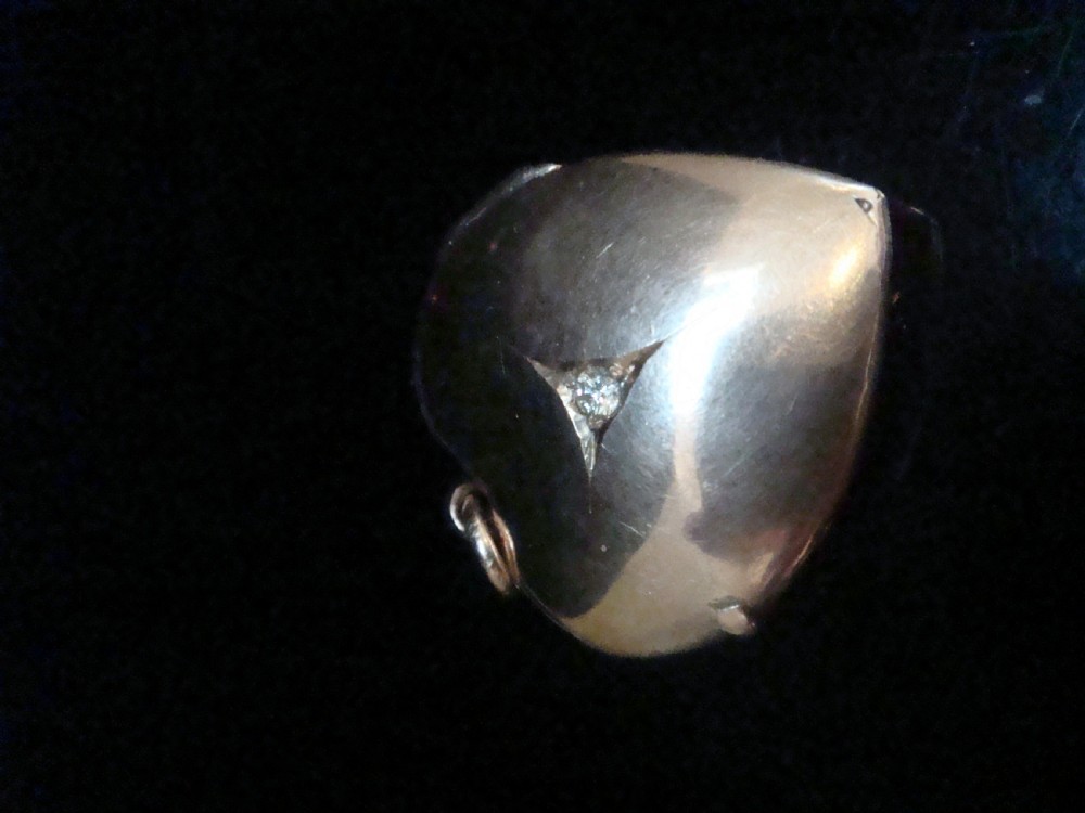 An Edwardian 9ct gold puffed heart locket featuring a centrally inset old cut diamond within a starburst setting. View IV