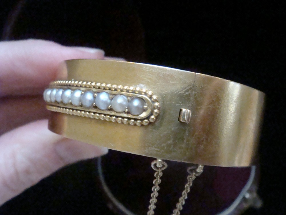 An antique 18ct gold cuff bracelet set with a central row of seed pearls framed by beaded borders, shown inside a velvet presentation box. View VII