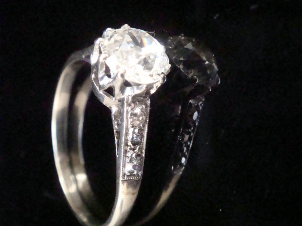 An Edwardian platinum solitaire ring featuring a round central diamond with small diamond accents set into the shoulders. View II