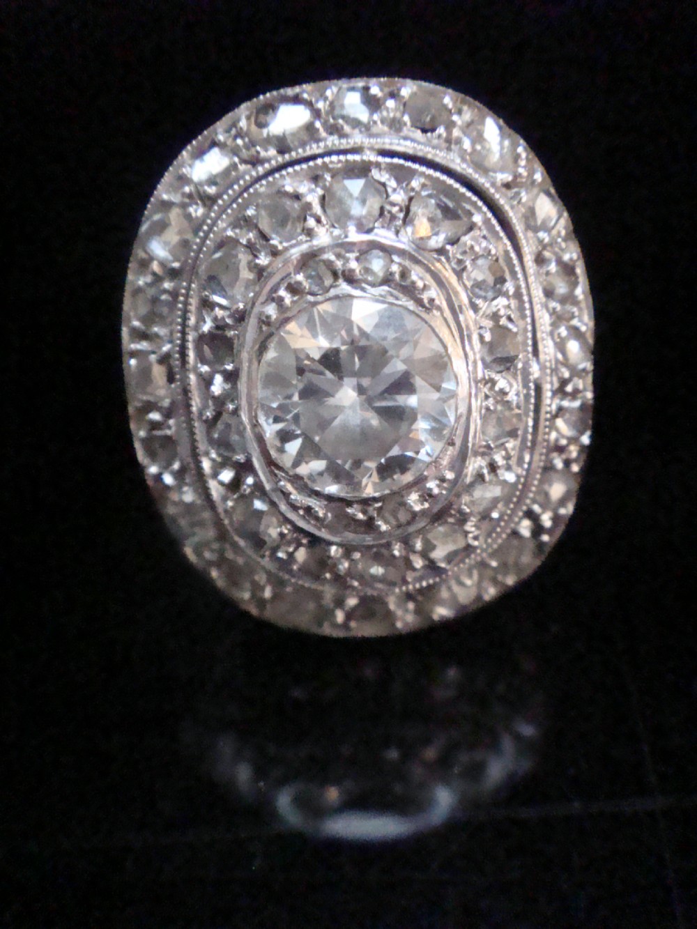 An Edwardian 18ct white gold target cluster ring set with a central old cut diamond surrounded by concentric tiers of diamonds and fine millegrain details. View II