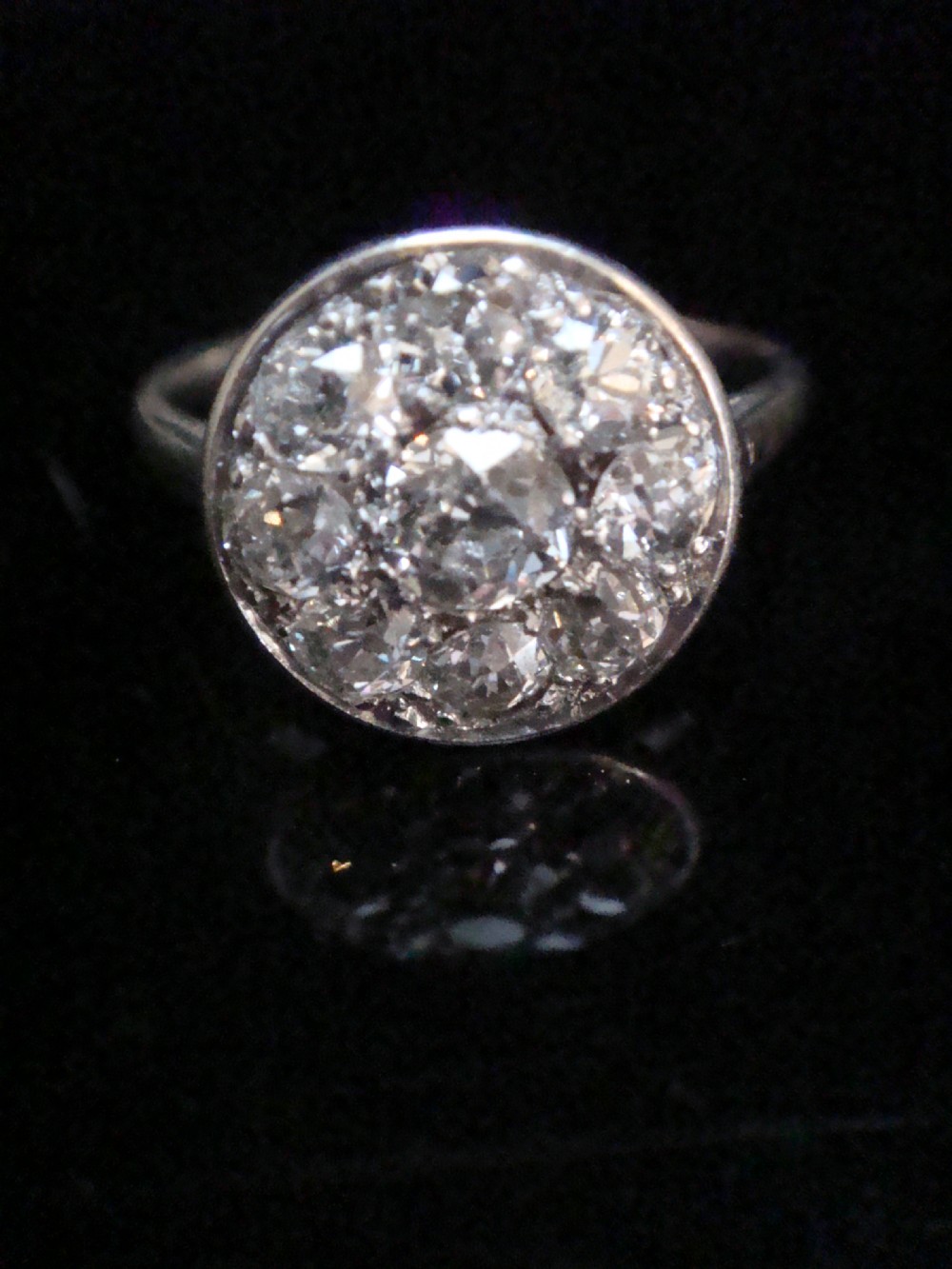 An Edwardian 18ct white gold ring featuring a circular cluster set with natural old cut diamonds.