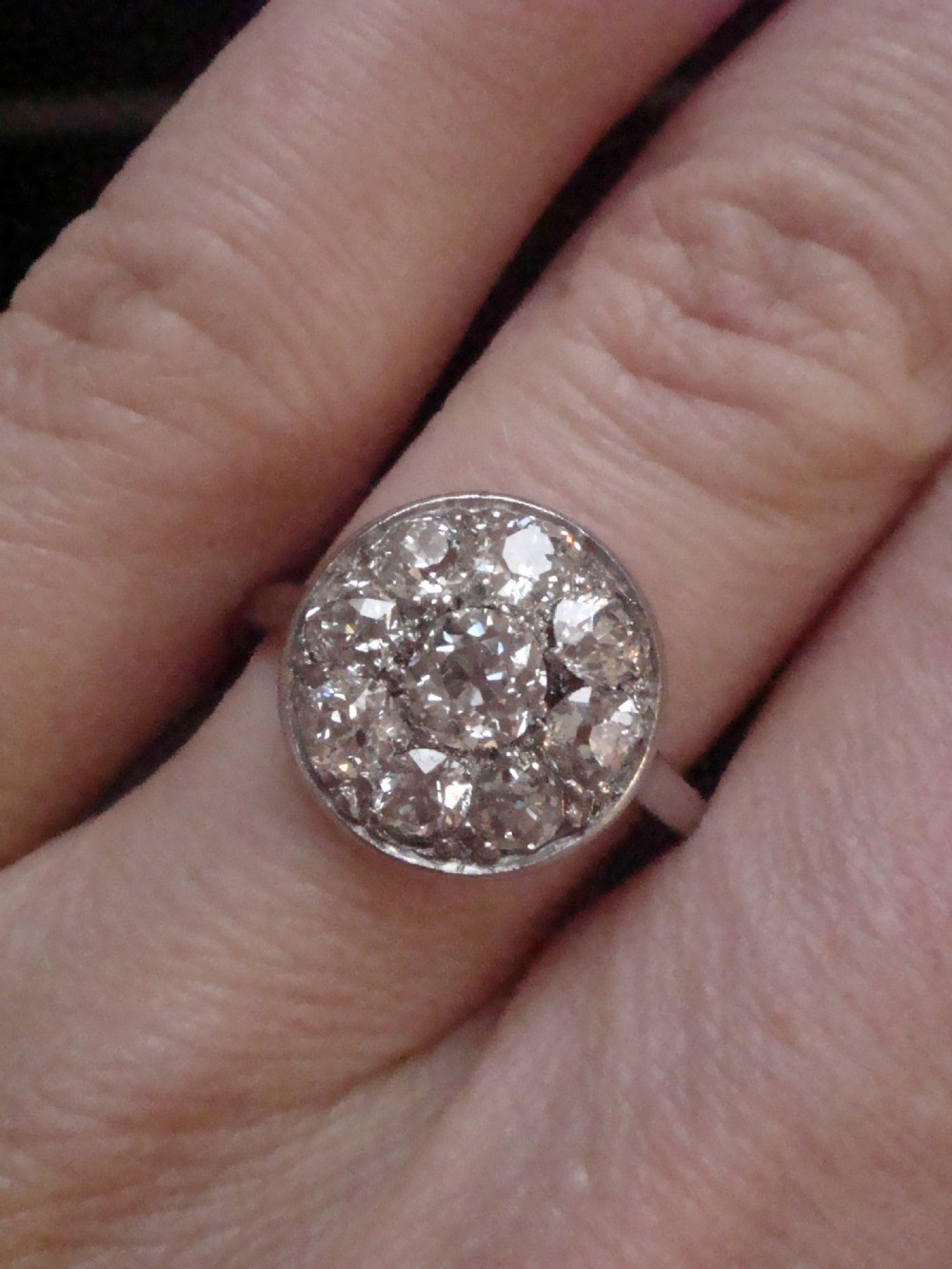 An Edwardian 18ct white gold ring featuring a circular cluster set with natural old cut diamonds. View III