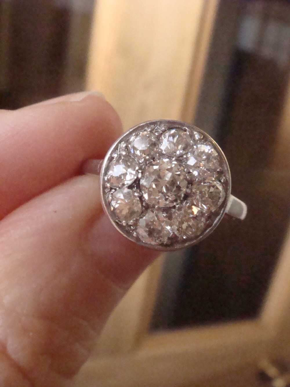 An Edwardian 18ct white gold ring featuring a circular cluster set with natural old cut diamonds. View V