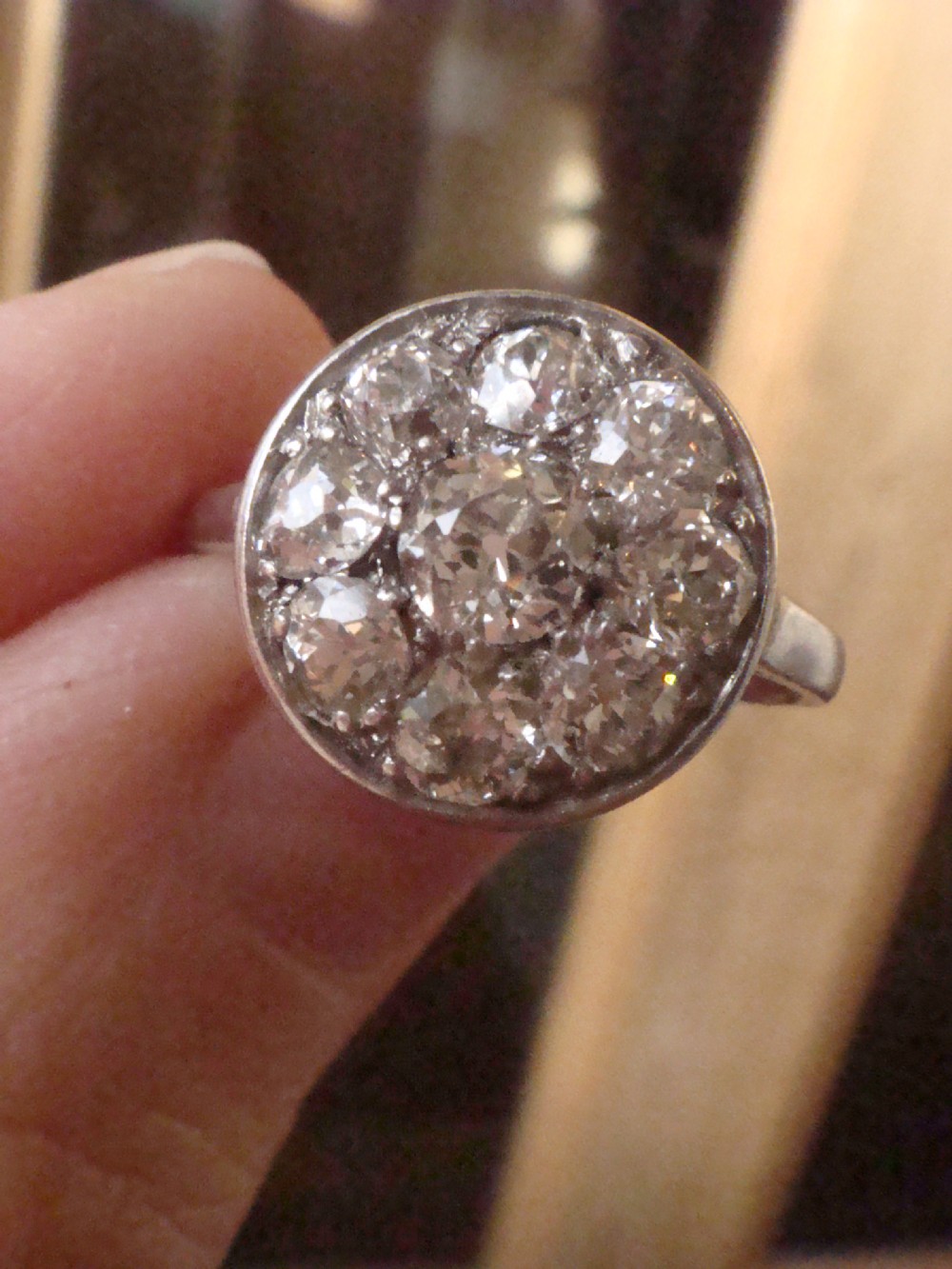 An Edwardian 18ct white gold ring featuring a circular cluster set with natural old cut diamonds. View VII