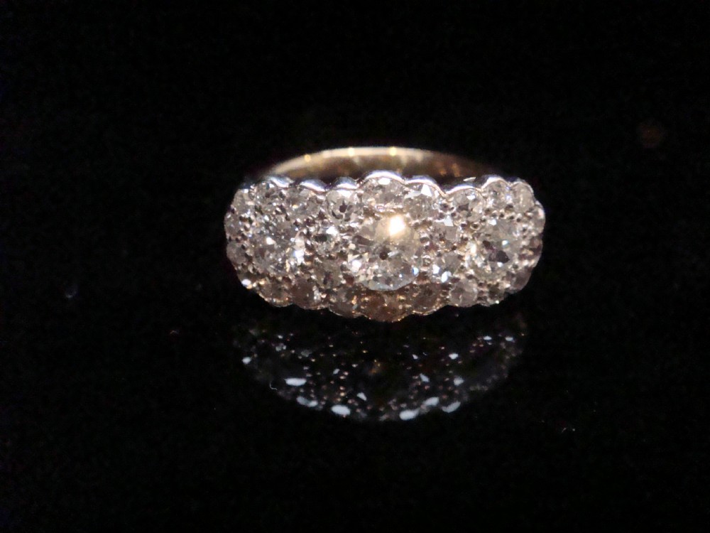 An Edwardian 18ct yellow gold and platinum cluster ring set with multiple natural old cut diamonds in an oval layout.