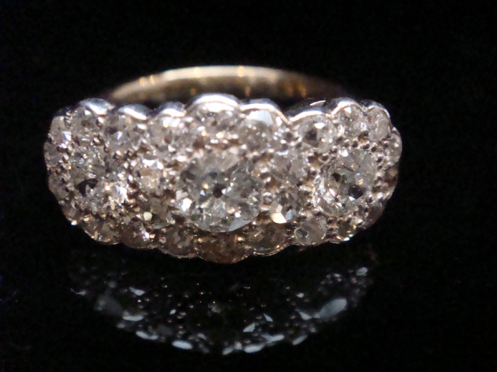 An Edwardian 18ct yellow gold and platinum cluster ring set with multiple natural old cut diamonds in an oval layout. View IV