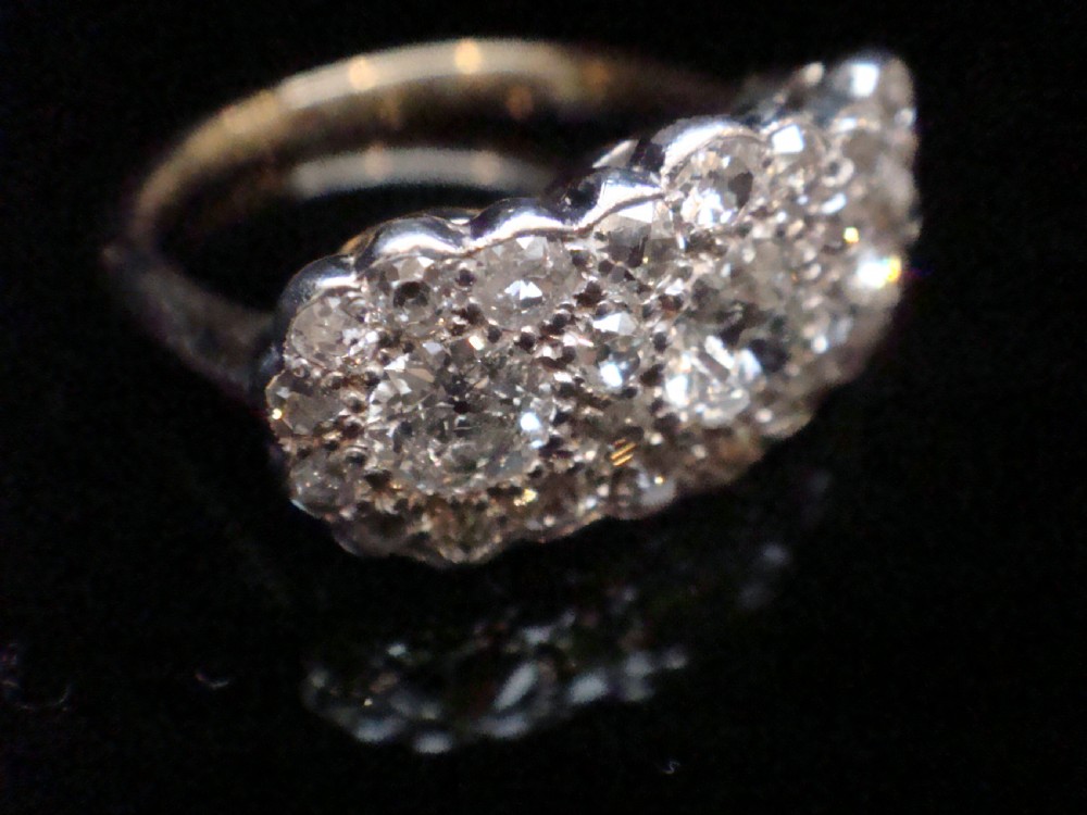 An Edwardian 18ct yellow gold and platinum cluster ring set with multiple natural old cut diamonds in an oval layout. View VI