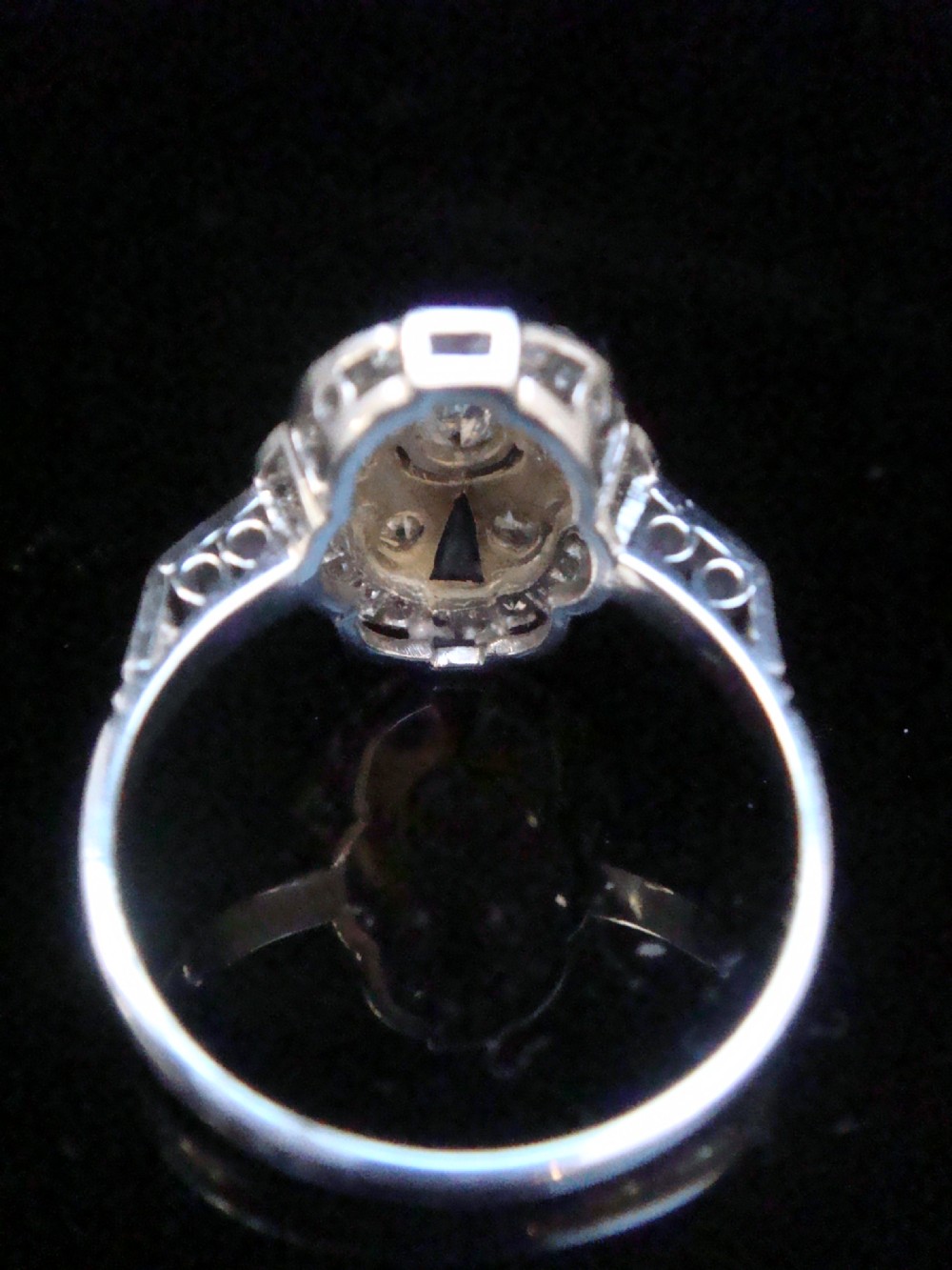 An Art Deco 18ct white gold oval cluster ring featuring central diamonds framed by geometric calibre-cut blue sapphires. View II