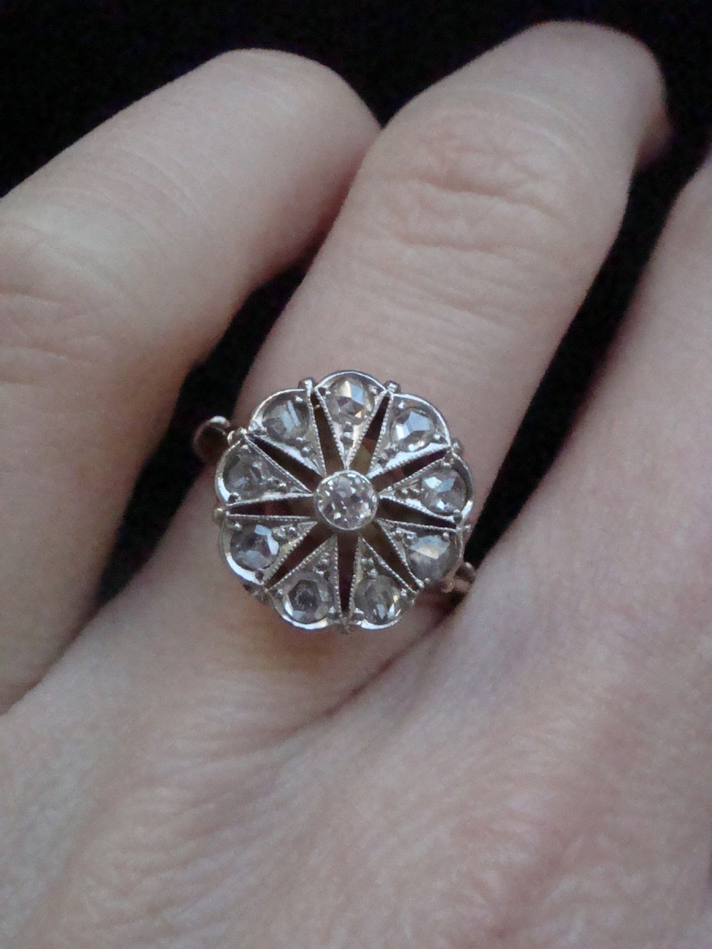 An Edwardian 18ct yellow gold and platinum ring featuring a floral starburst cluster set with old-cut diamonds. View IV