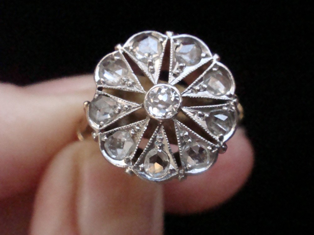 An Edwardian 18ct yellow gold and platinum ring featuring a floral starburst cluster set with old-cut diamonds. View VII