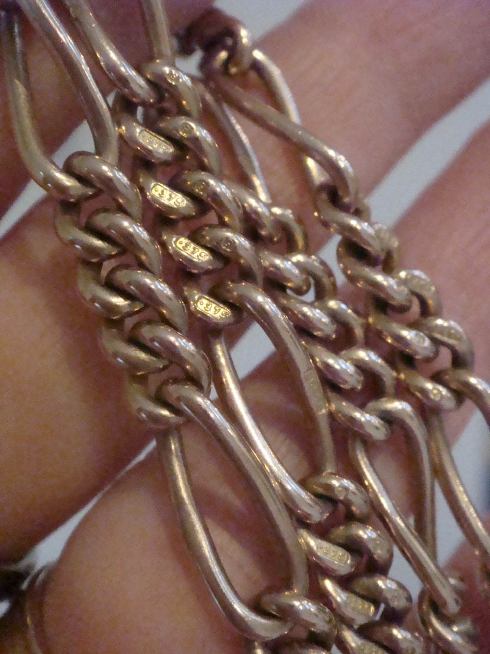 An Edwardian 9ct yellow gold Figaro link double Albert chain featuring a central T-bar, floating ring, and two dog clip fasteners. View V