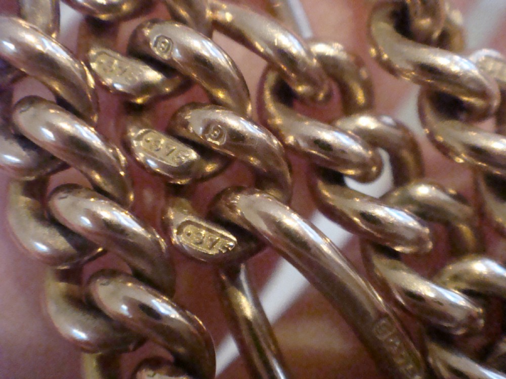 An Edwardian 9ct yellow gold Figaro link double Albert chain featuring a central T-bar, floating ring, and two dog clip fasteners. View IX