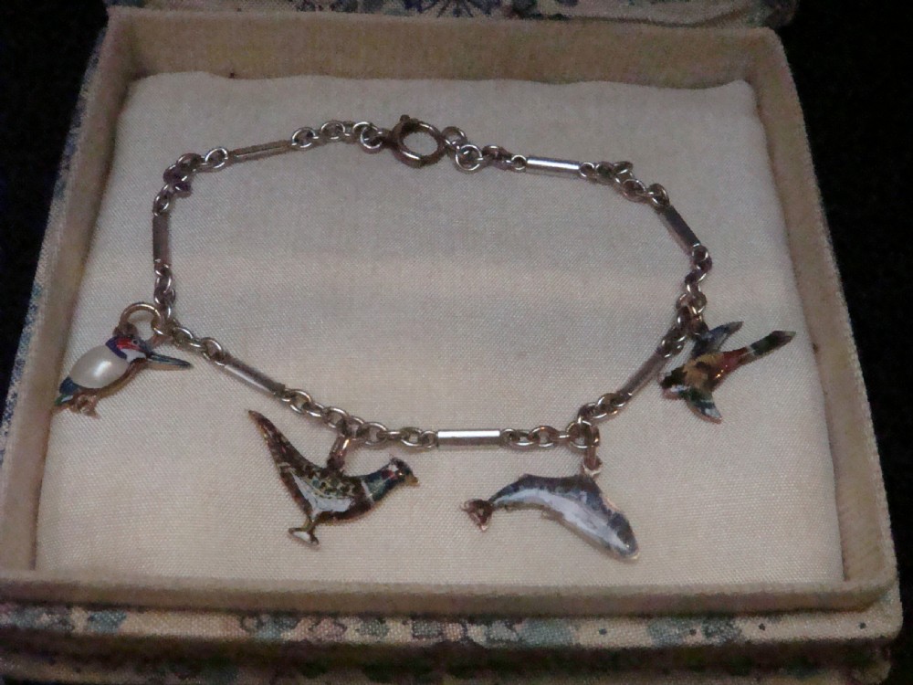 An Edwardian gold link chain bracelet featuring polychrome enamelled wildlife charms including game birds and a fish.