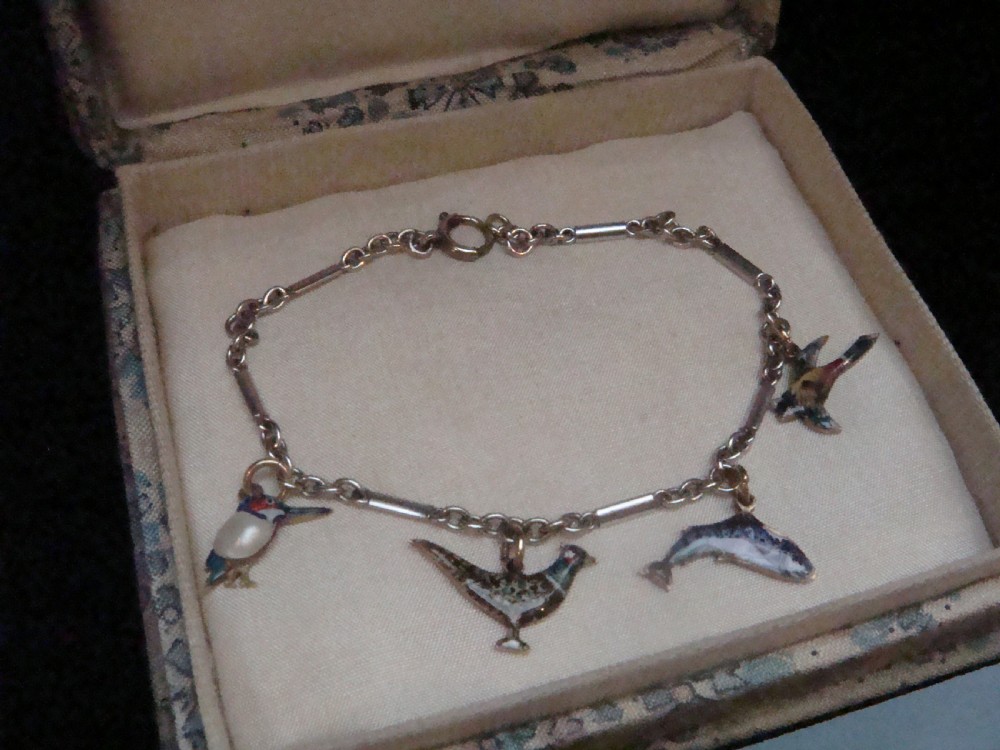 An Edwardian gold link chain bracelet featuring polychrome enamelled wildlife charms including game birds and a fish. View II