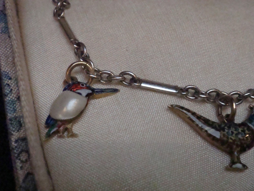 An Edwardian gold link chain bracelet featuring polychrome enamelled wildlife charms including game birds and a fish. View III