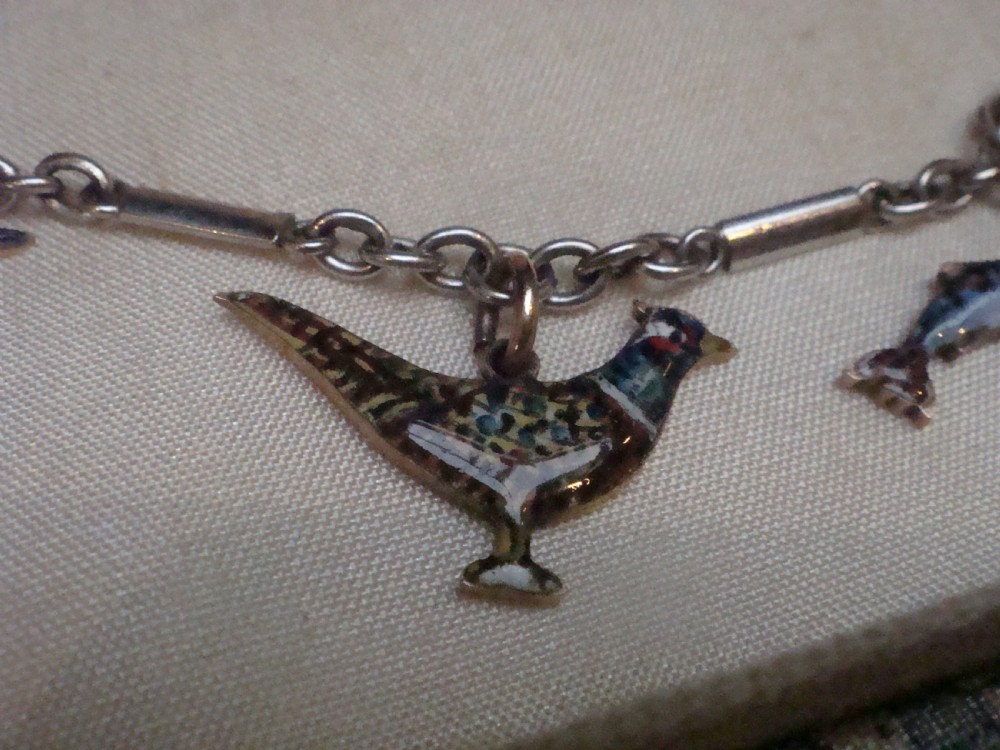 An Edwardian gold link chain bracelet featuring polychrome enamelled wildlife charms including game birds and a fish. View IV