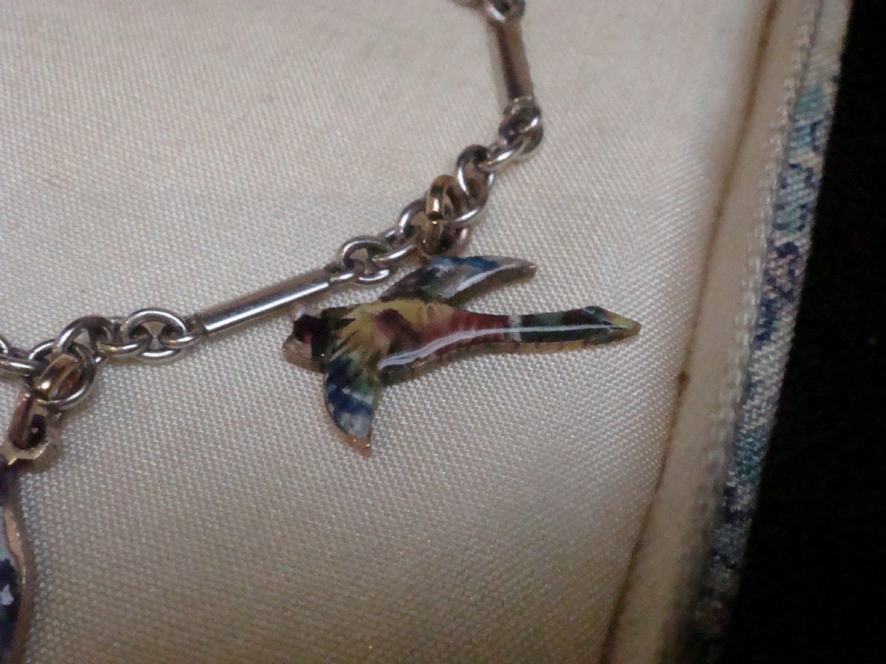 An Edwardian gold link chain bracelet featuring polychrome enamelled wildlife charms including game birds and a fish. View VI
