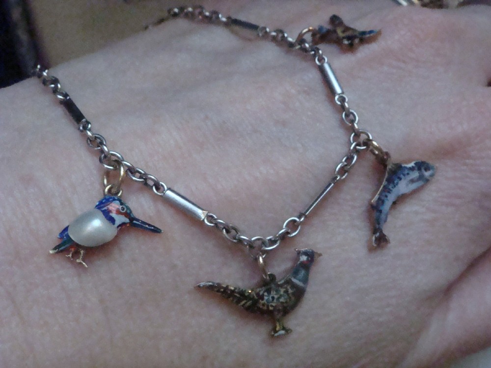 An Edwardian gold link chain bracelet featuring polychrome enamelled wildlife charms including game birds and a fish. View IX