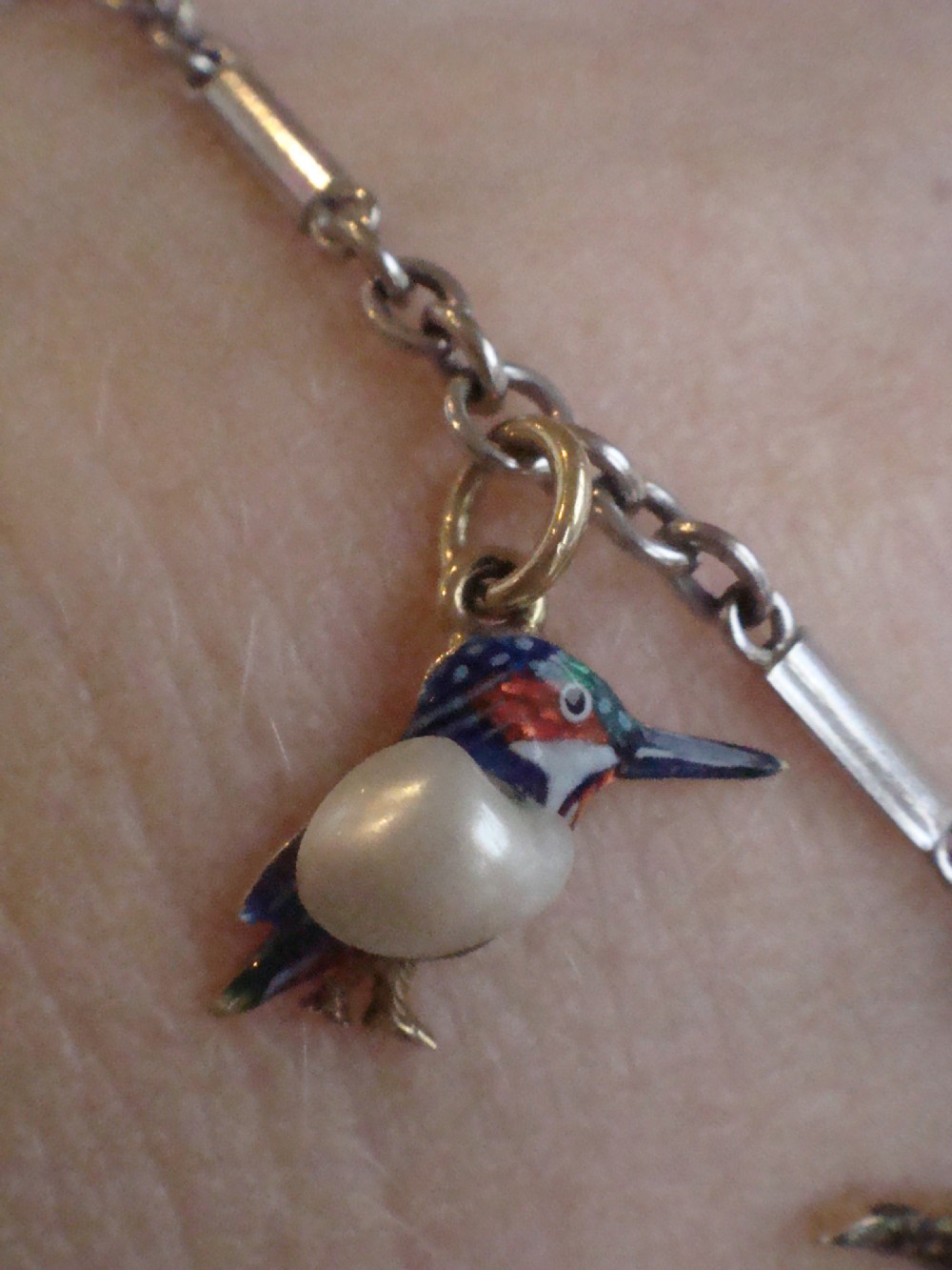 An Edwardian gold link chain bracelet featuring polychrome enamelled wildlife charms including game birds and a fish. View XI