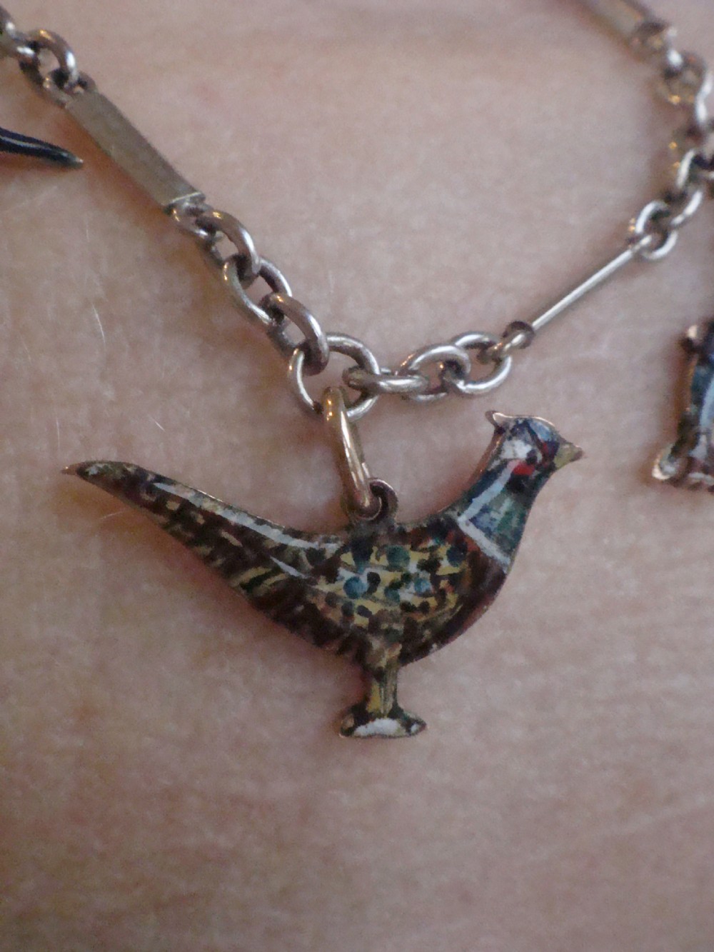 An Edwardian gold link chain bracelet featuring polychrome enamelled wildlife charms including game birds and a fish. View XII
