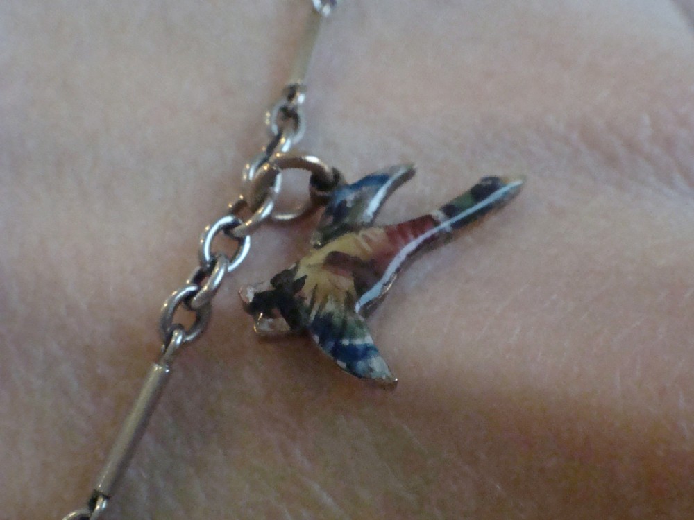 An Edwardian gold link chain bracelet featuring polychrome enamelled wildlife charms including game birds and a fish. View XIV