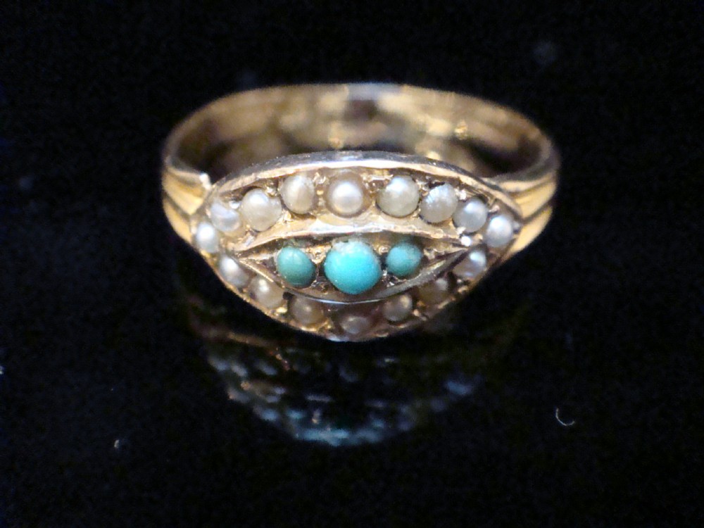 An Edwardian 9ct gold ring featuring a central eye-shaped navette motif set with turquoise cabochons and surrounded by small seed pearls.