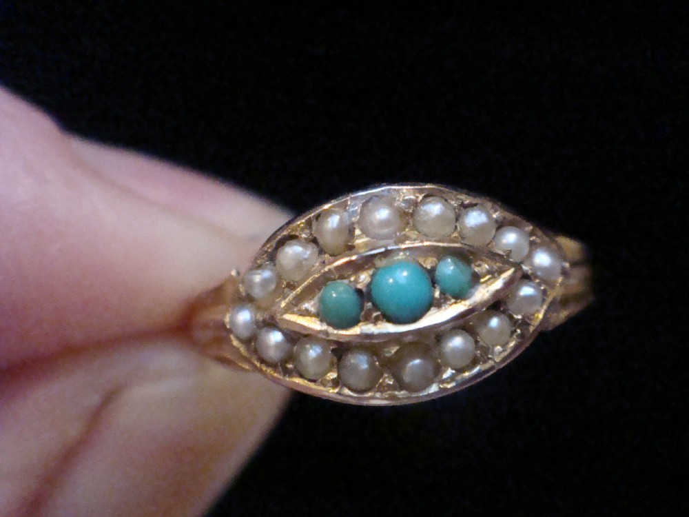 An Edwardian 9ct gold ring featuring a central eye-shaped navette motif set with turquoise cabochons and surrounded by small seed pearls. View IV
