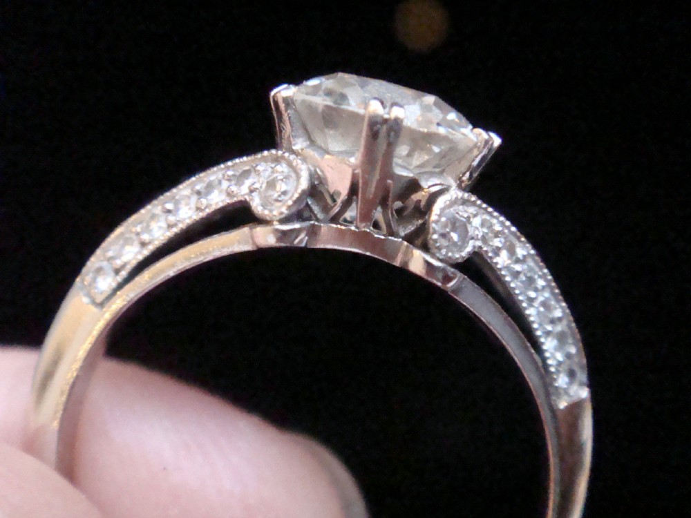 An Art Deco platinum solitaire ring featuring a large transitional-cut central diamond flanked by two triangular blue sapphires. View XI