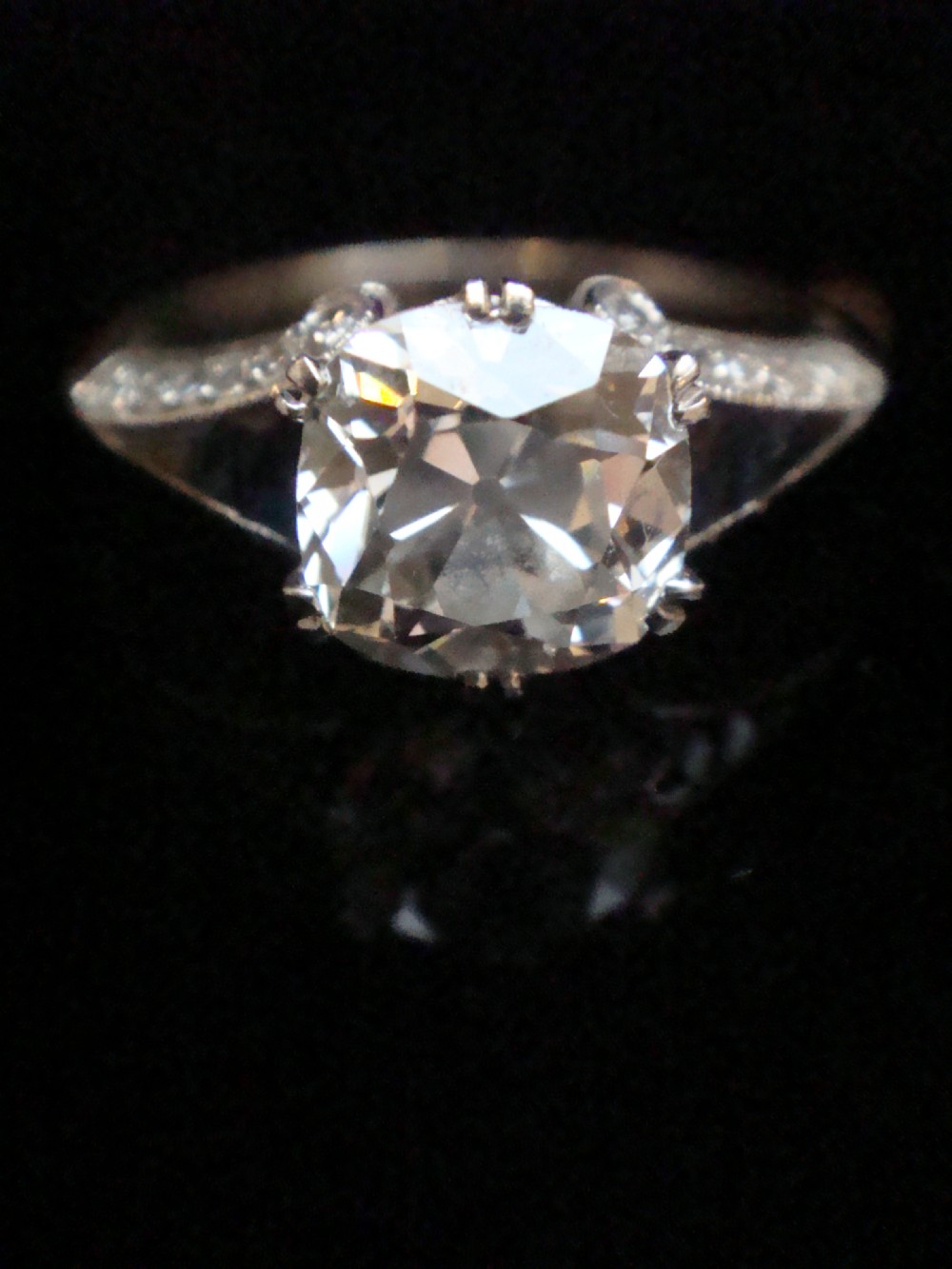 An Art Deco platinum solitaire ring featuring a large transitional-cut central diamond flanked by two triangular blue sapphires. View XIV