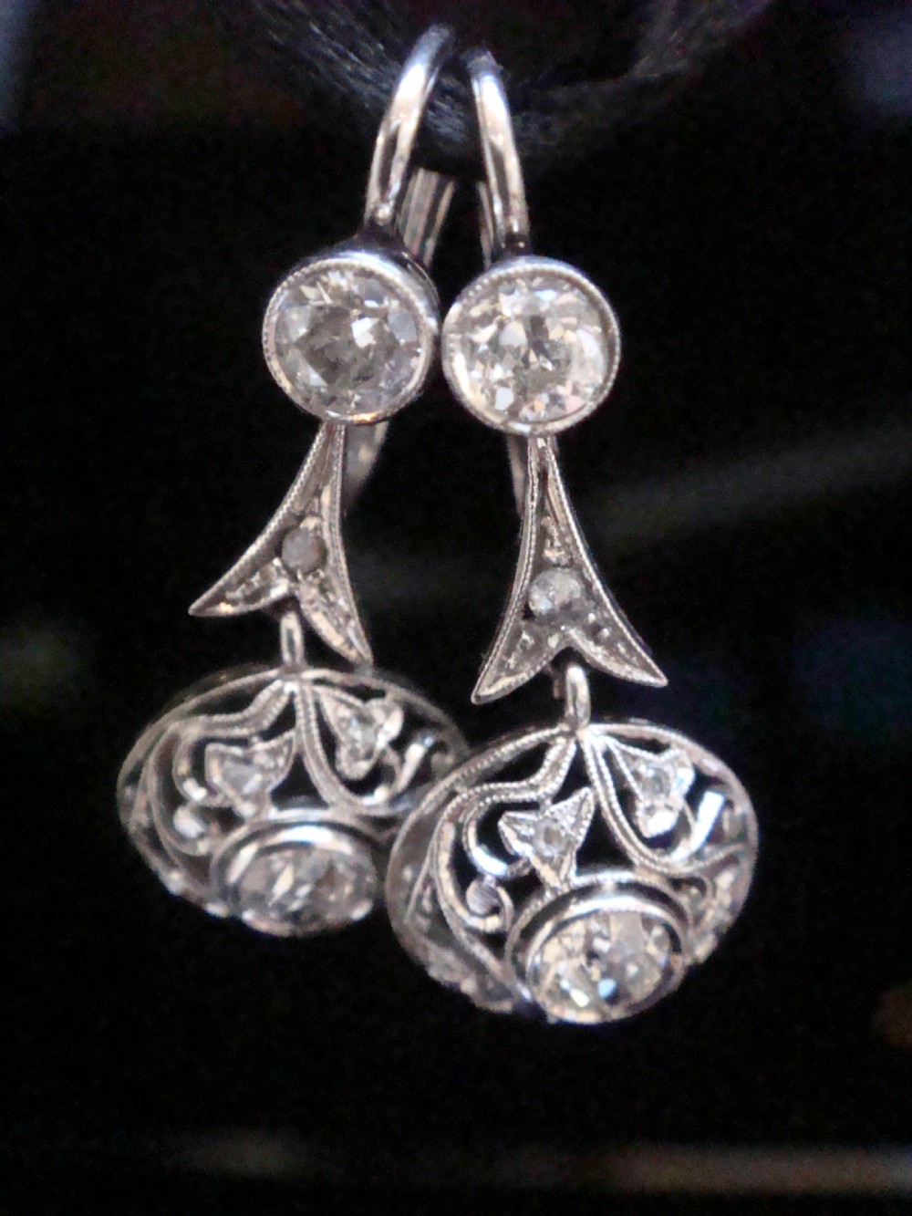 A pair of Edwardian 18ct white gold drop earrings featuring old cut diamonds set within circular openwork filigree mounts. View II