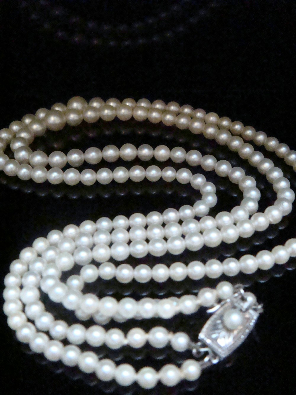 A double strand graduated white cultured pearl necklace featuring an ornate silver box clasp set with a single pearl. View II