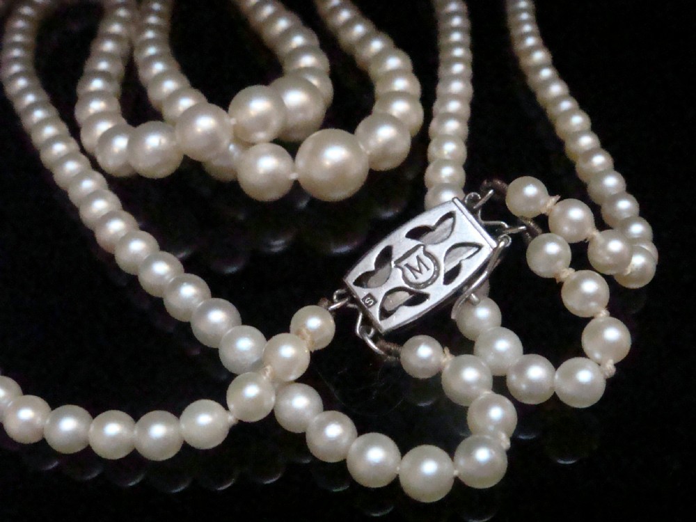 A double strand graduated white cultured pearl necklace featuring an ornate silver box clasp set with a single pearl. View IV