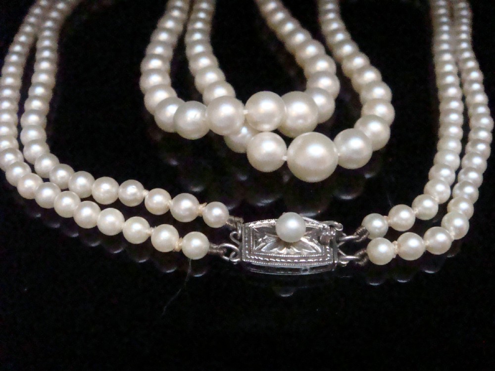 A double strand graduated white cultured pearl necklace featuring an ornate silver box clasp set with a single pearl. View V