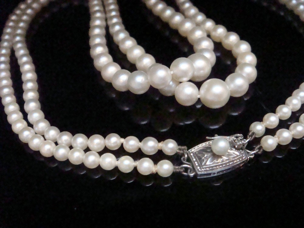 A double strand graduated white cultured pearl necklace featuring an ornate silver box clasp set with a single pearl. View VI