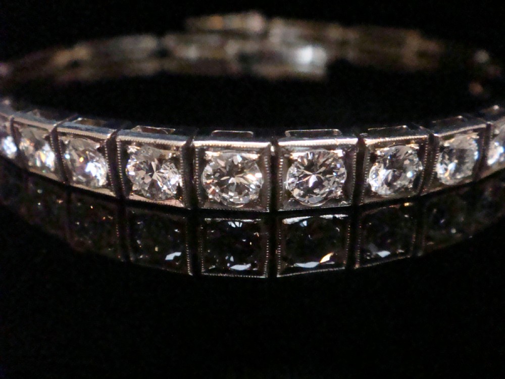 An Edwardian 18ct white gold line bracelet featuring a continuous row of round brilliant cut diamonds set in square box links. View V