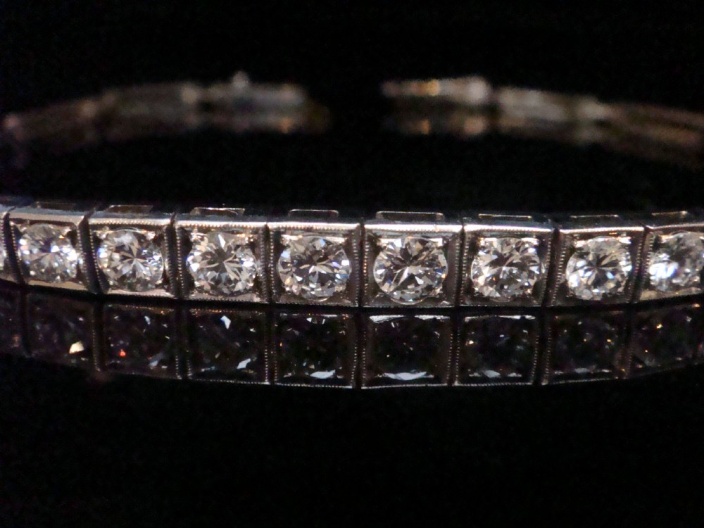 An Edwardian 18ct white gold line bracelet featuring a continuous row of round brilliant cut diamonds set in square box links. View VI