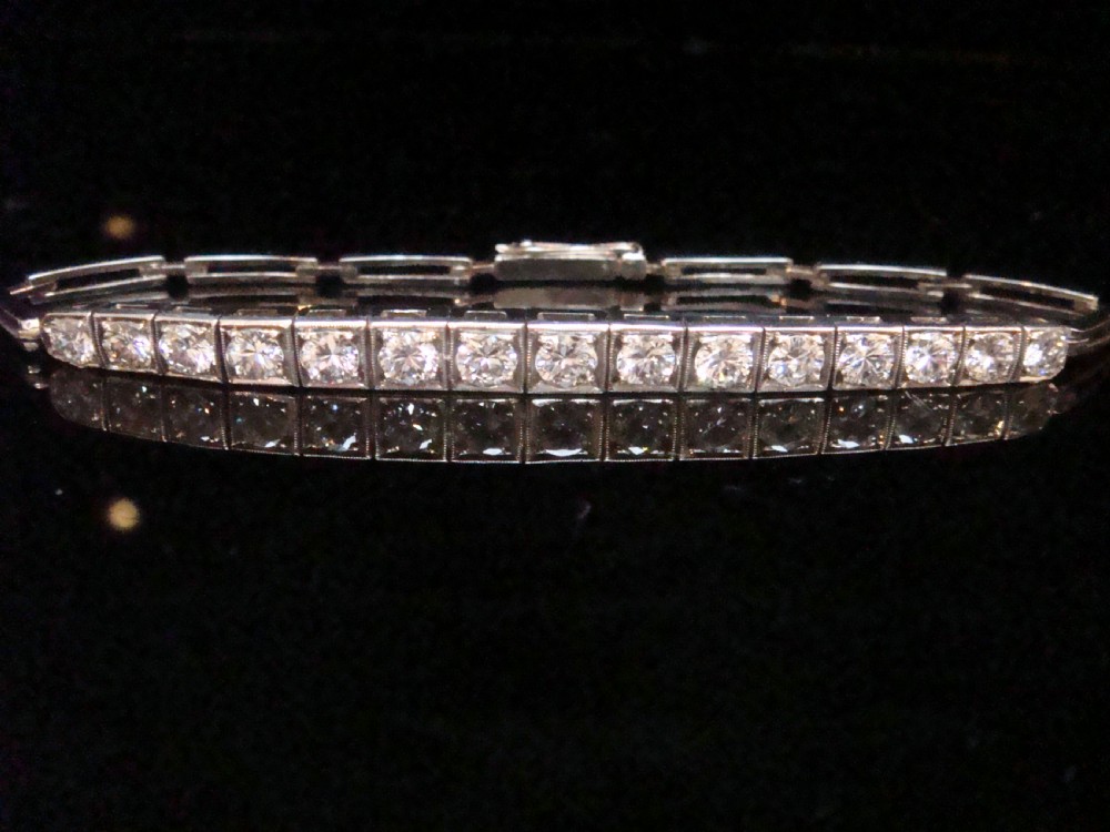 An Edwardian 18ct white gold line bracelet featuring a continuous row of round brilliant cut diamonds set in square box links.