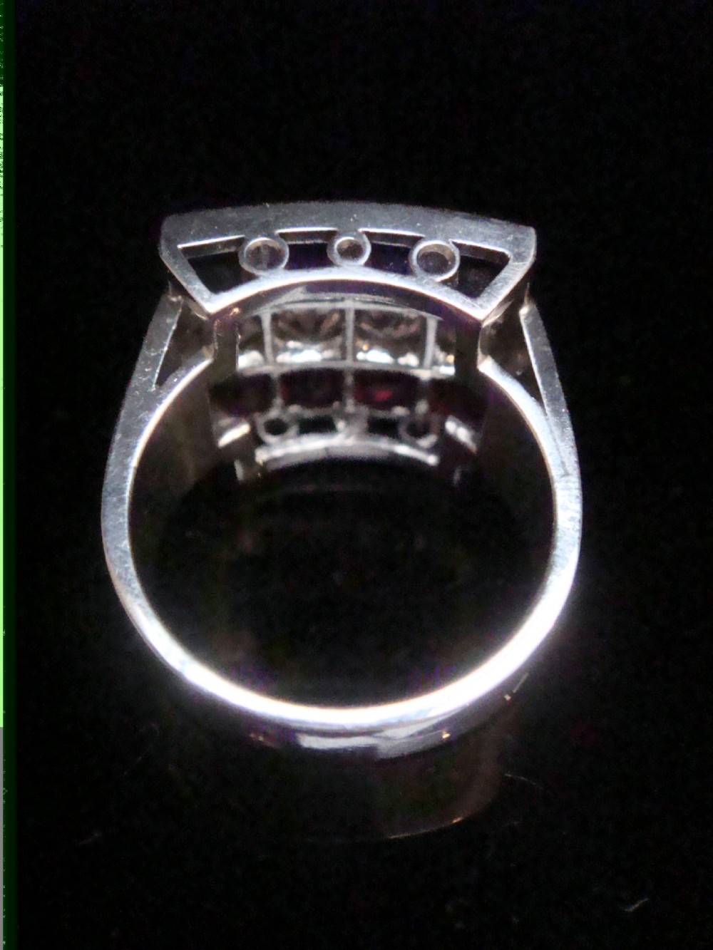 An Art Deco platinum rectangular plaque ring set with horizontal rows of red rubies, white diamonds, and blue sapphires. View II