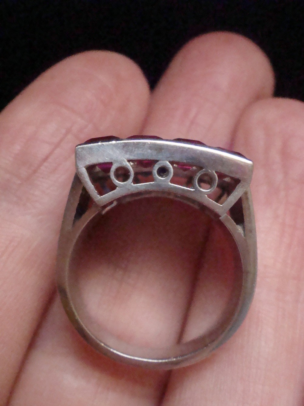 An Art Deco platinum rectangular plaque ring set with horizontal rows of red rubies, white diamonds, and blue sapphires. View VI