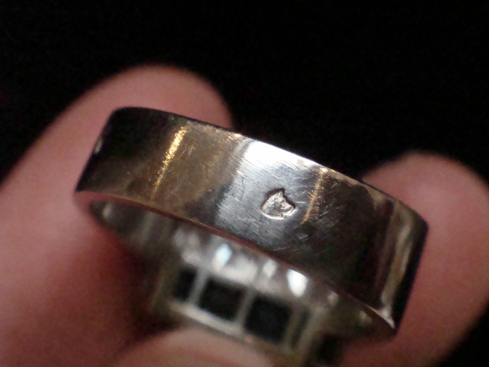 An Art Deco platinum rectangular plaque ring set with horizontal rows of red rubies, white diamonds, and blue sapphires. View VII