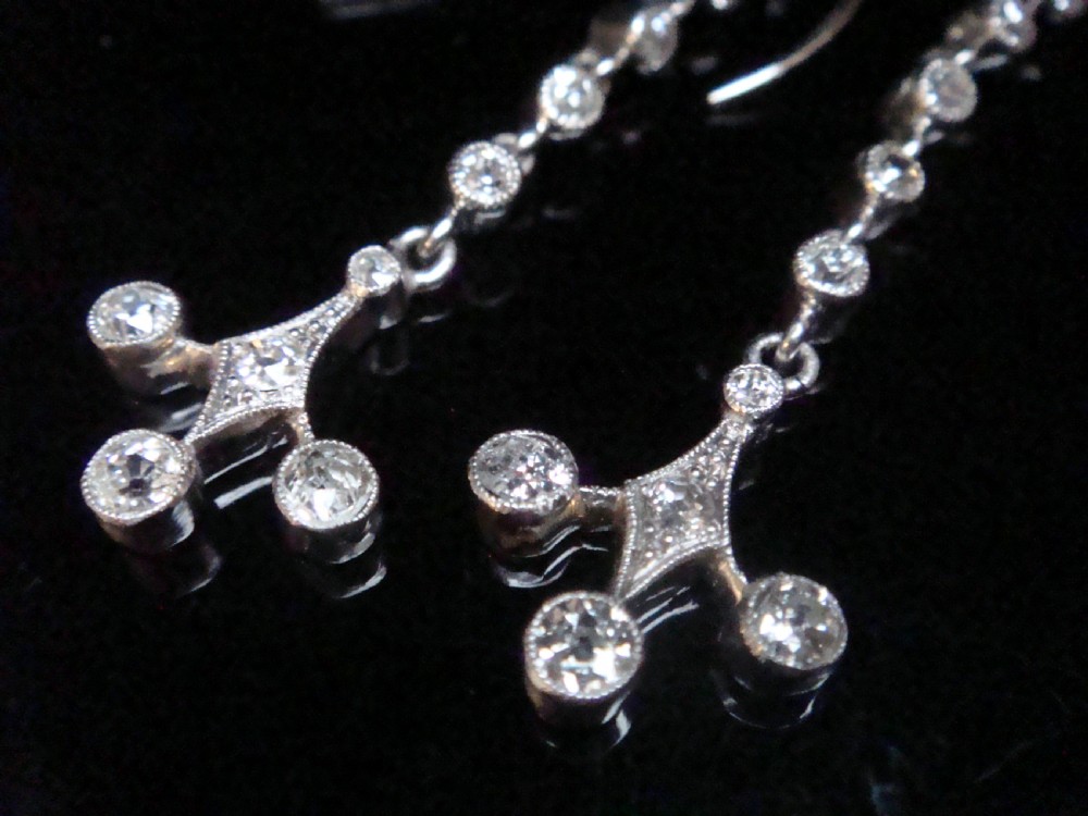 Pair of Edwardian platinum drop earrings featuring articulated lines of bezel-set round old cut diamonds terminating in geometric drops with hook fastenings. View III