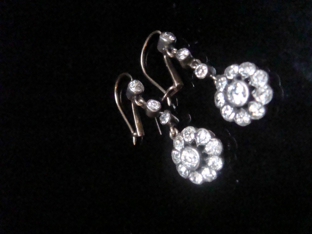 A pair of Edwardian silver and gold drop earrings featuring articulated strands of old cut diamonds leading to floral cluster drops. View IV