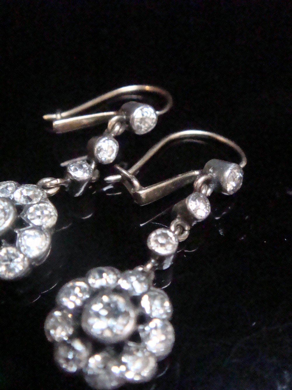 A pair of Edwardian silver and gold drop earrings featuring articulated strands of old cut diamonds leading to floral cluster drops. View II
