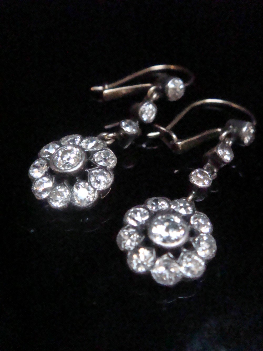 A pair of Edwardian silver and gold drop earrings featuring articulated strands of old cut diamonds leading to floral cluster drops. View III