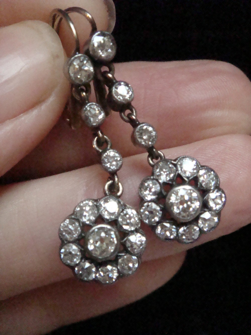 A pair of Edwardian silver and gold drop earrings featuring articulated strands of old cut diamonds leading to floral cluster drops. View VI