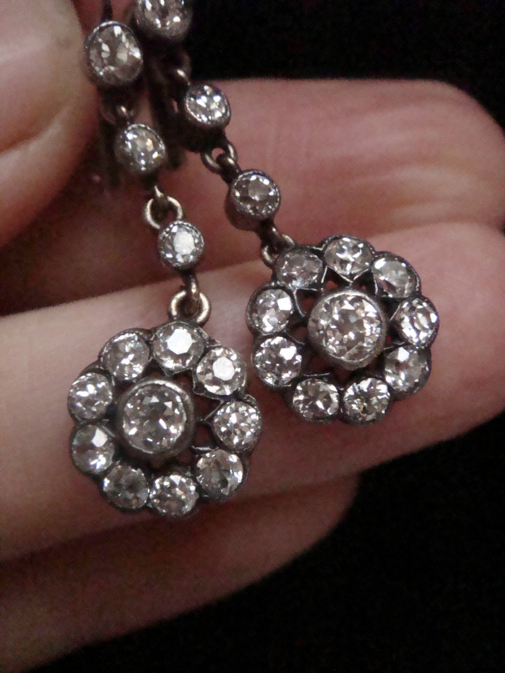 A pair of Edwardian silver and gold drop earrings featuring articulated strands of old cut diamonds leading to floral cluster drops. View VIII