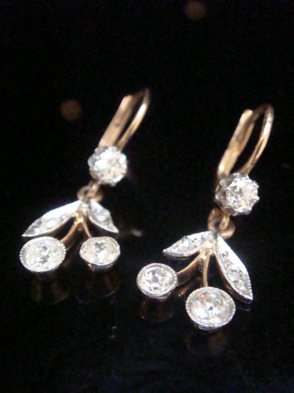 A pair of French Edwardian 18ct yellow gold drop earrings featuring a botanical leaf design set with old cut diamonds. View VI