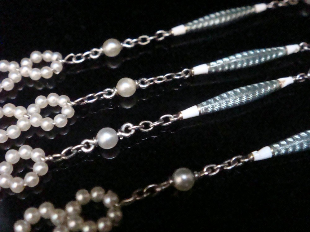An Edwardian platinum chain detailed with small pearl clusters, single saltwater pearls, and delicate turquoise guilloche enamel links.