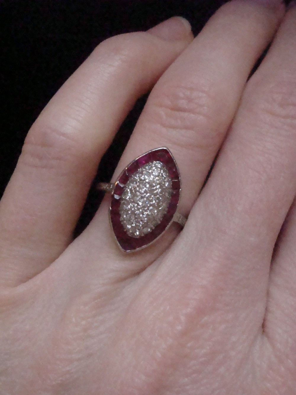 An Art Deco marquise cluster ring featuring a central diamond pave setting surrounded by a border of calibre-cut red rubies. View VIII